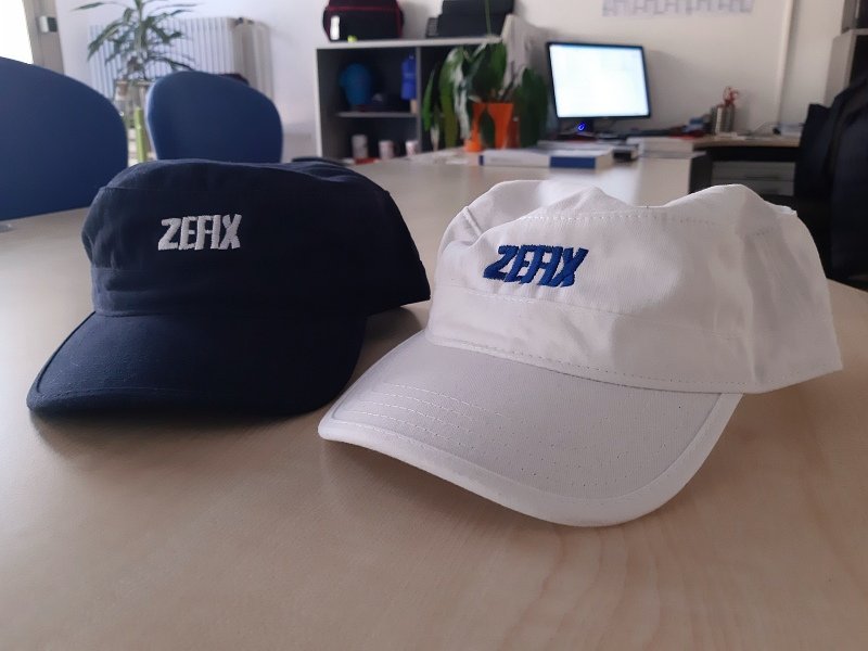 Zwei Caps in Weiß und Marineblau mit blauer Stickerei