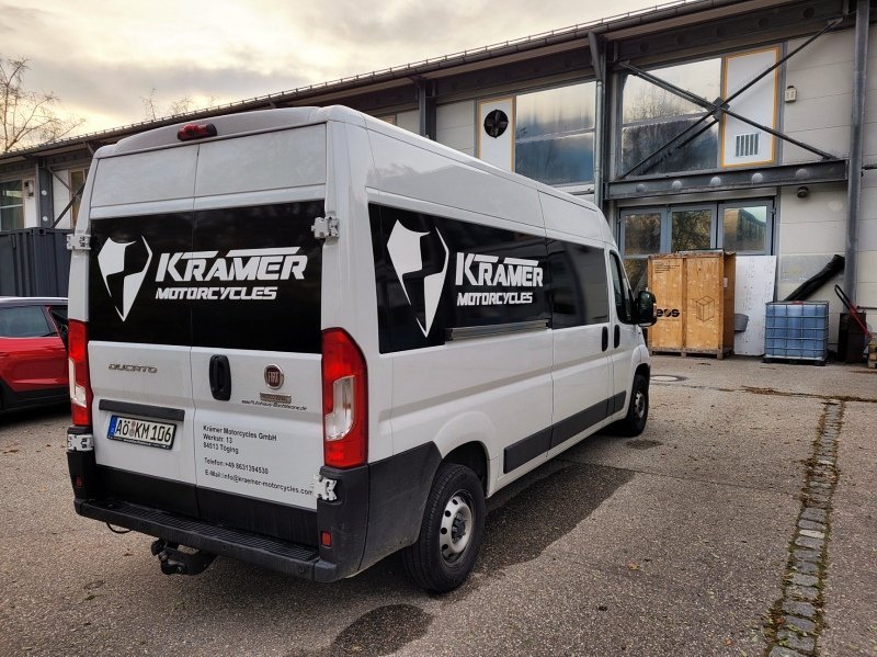 Weißer Kastenwagen mit schwarzer Folienbeschriftung