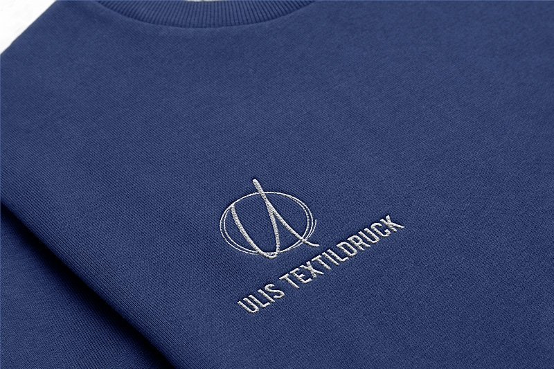 Marineblauer Pullover mit hellgrau gesticktem Ulis-Logo in Nahaufnahme